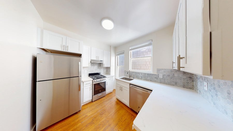 A kitchen with a stainless steel refrigerator and wooden floors.